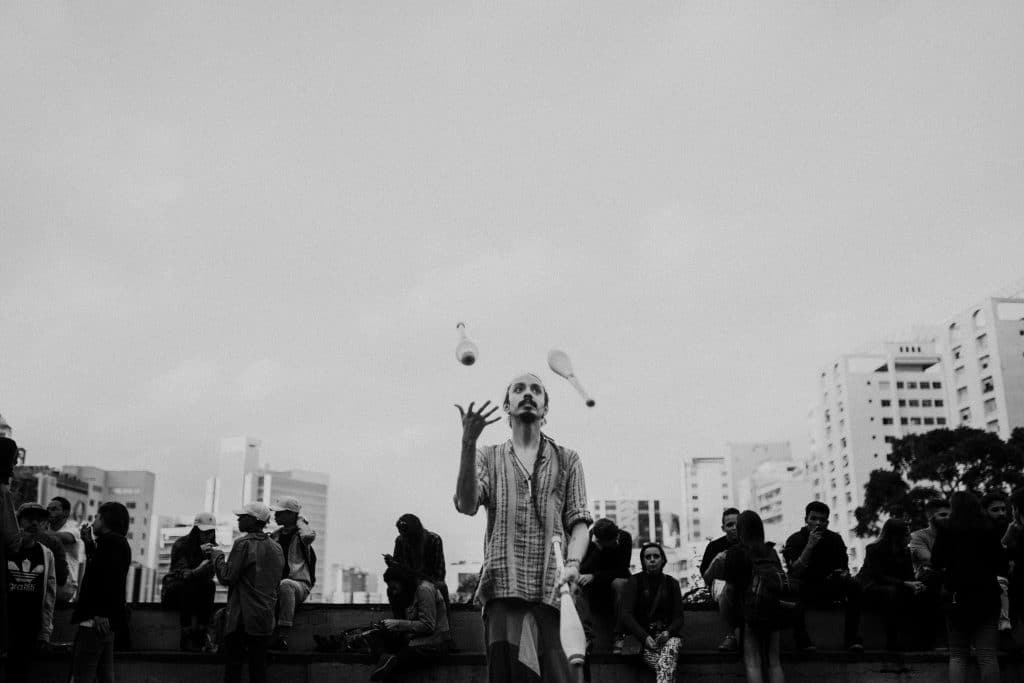 A street performer skillfully juggles in a bustling city scene, captivating onlookers.