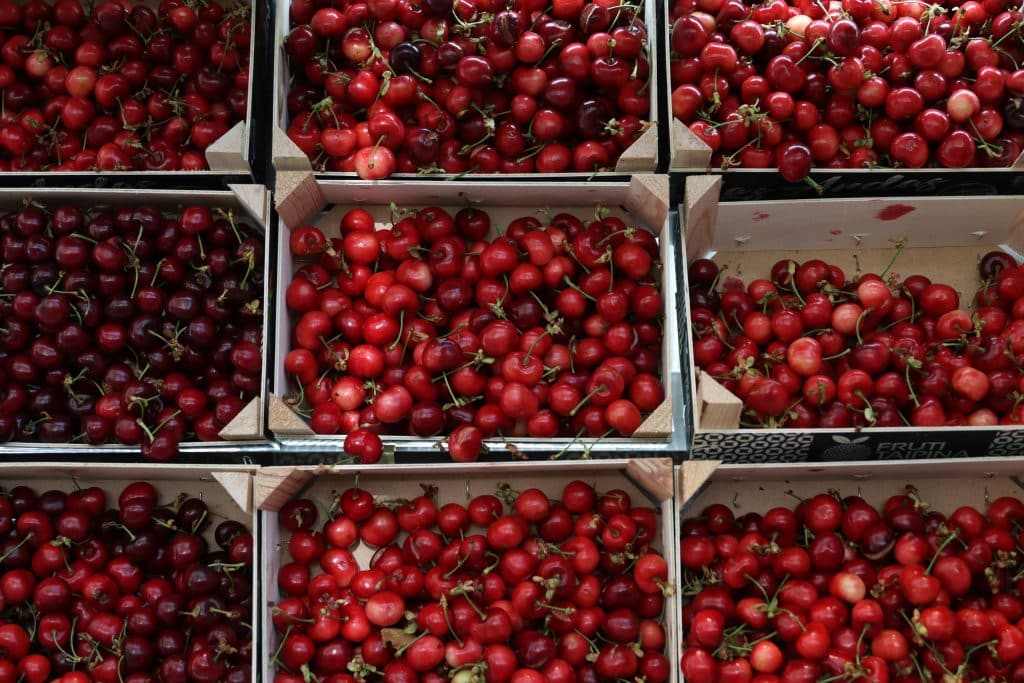 A top view of fresh red cherries displayed in wooden boxes at a Porto market.
